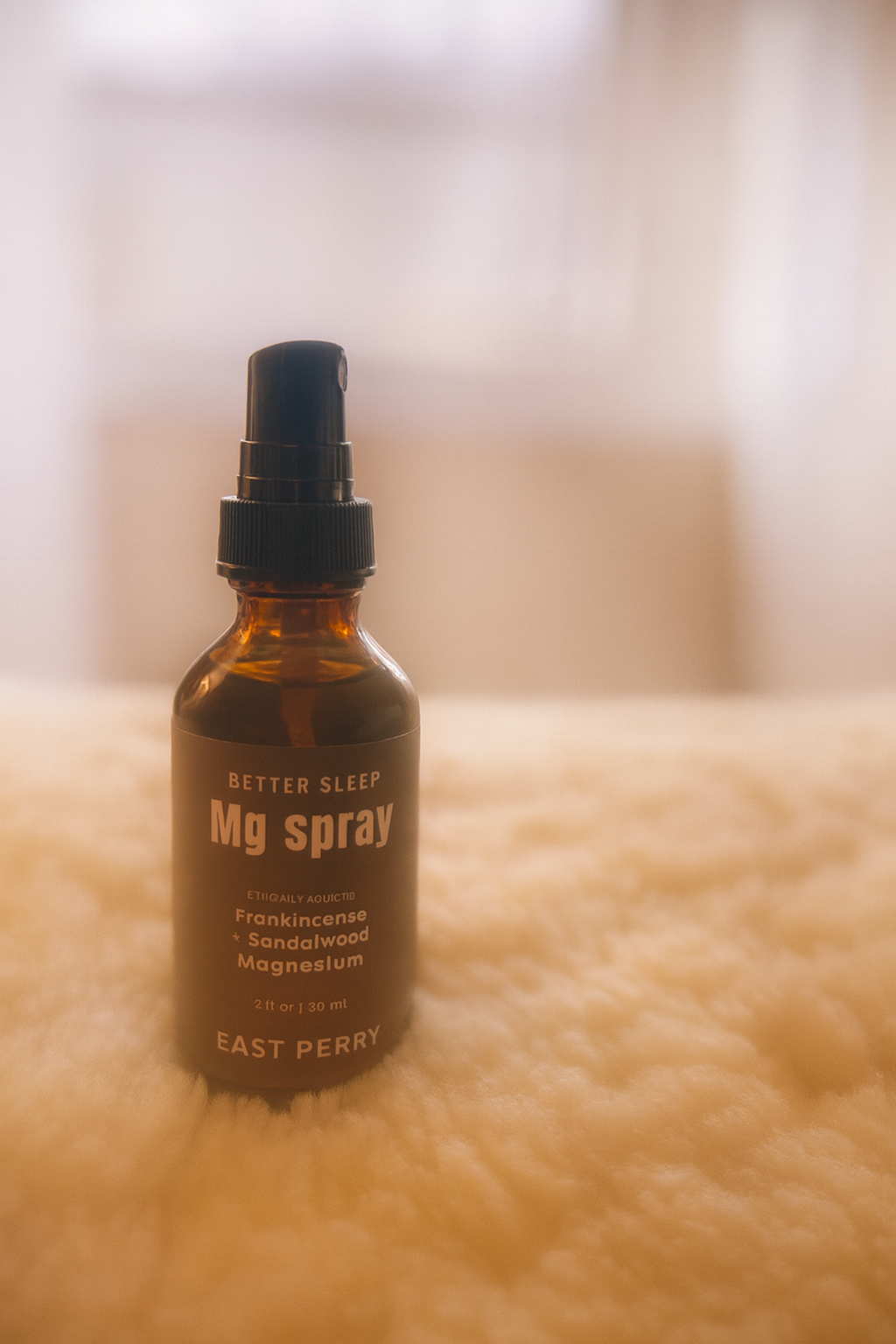 A brown glass spray bottle labeled East Perry Better Sleep Magnesium Spray rests on a soft, fluffy surface with a blurred, warm-toned background.