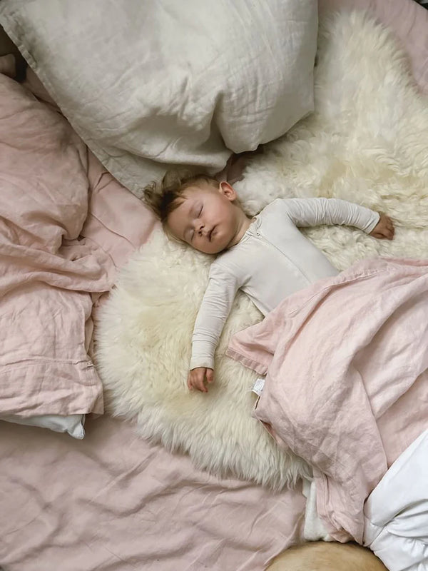 Child sleeping on a bright ivory nursery sheepskin