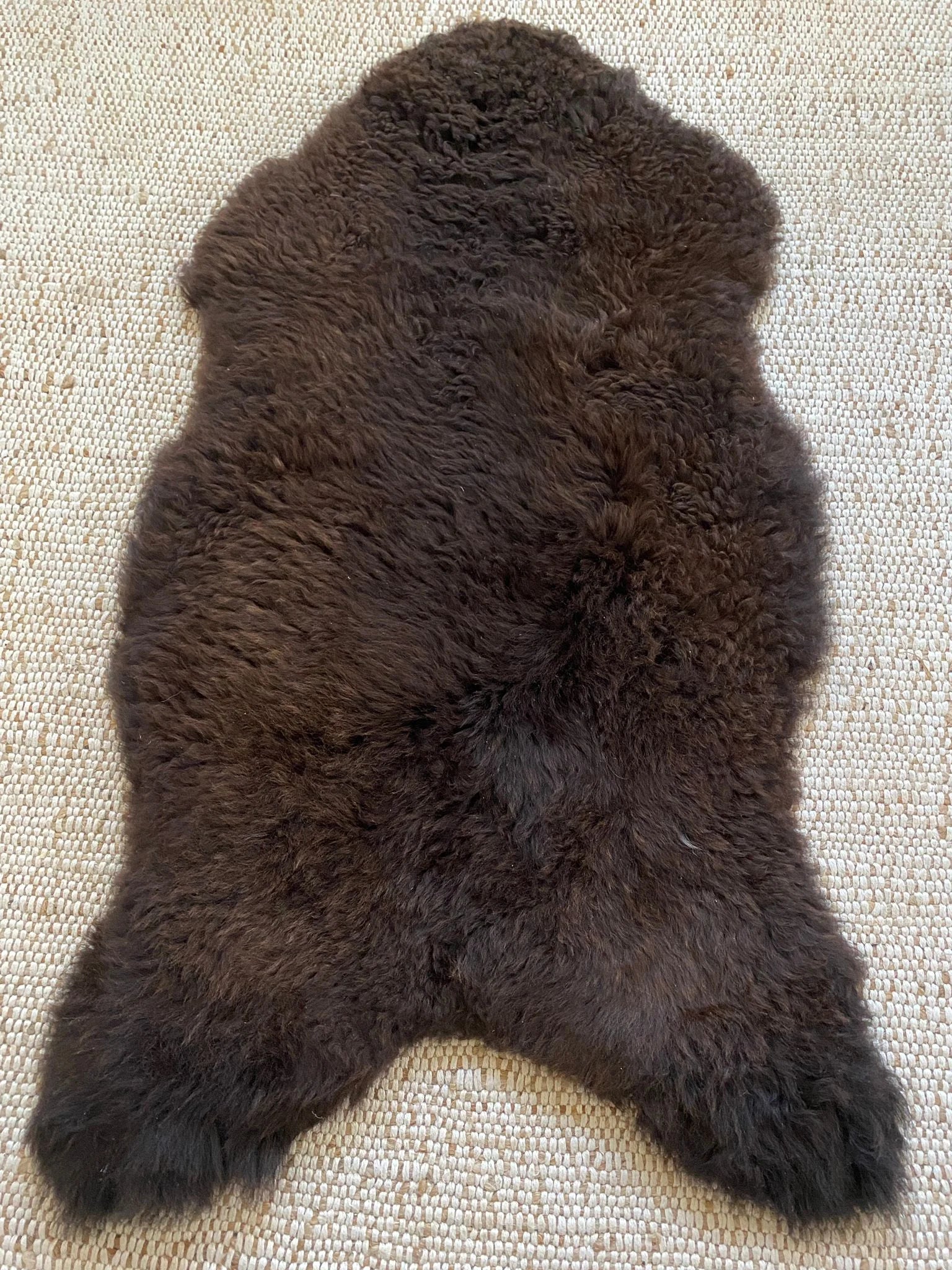 Top view of dark brown fur rug on a textured surface