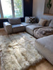 Gray sectional sofa with cushions on creamy ivory sheepskin bed cover rug