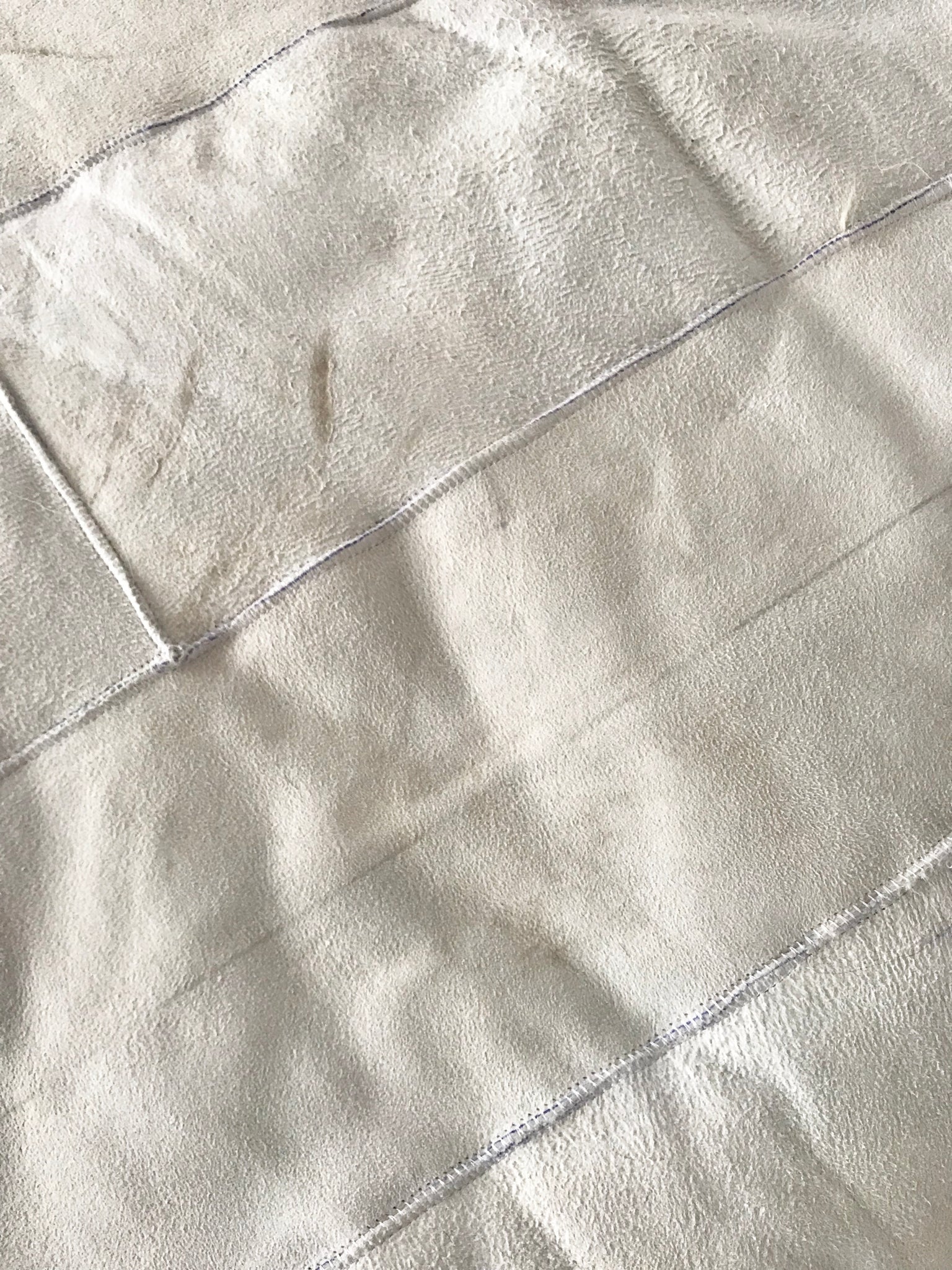 Rear-view close-up of creamy ivory sheepskin bed cover rug
