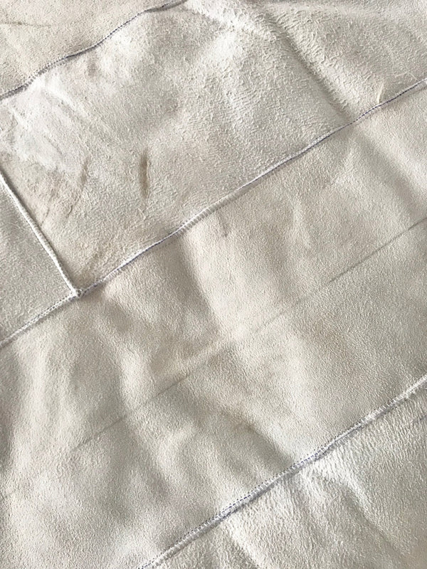 Rear-view close-up of creamy ivory sheepskin bed cover rug