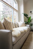 Beige sofa with decorative pillows with double sheepskin in white