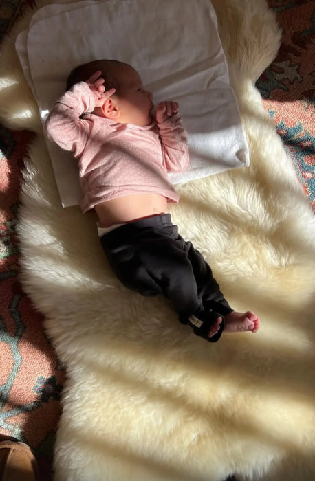 Baby lying on a white rug family bundles