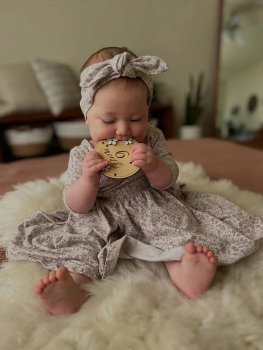 Baby in a floral outfit sitting on a fluffy rag family bundles