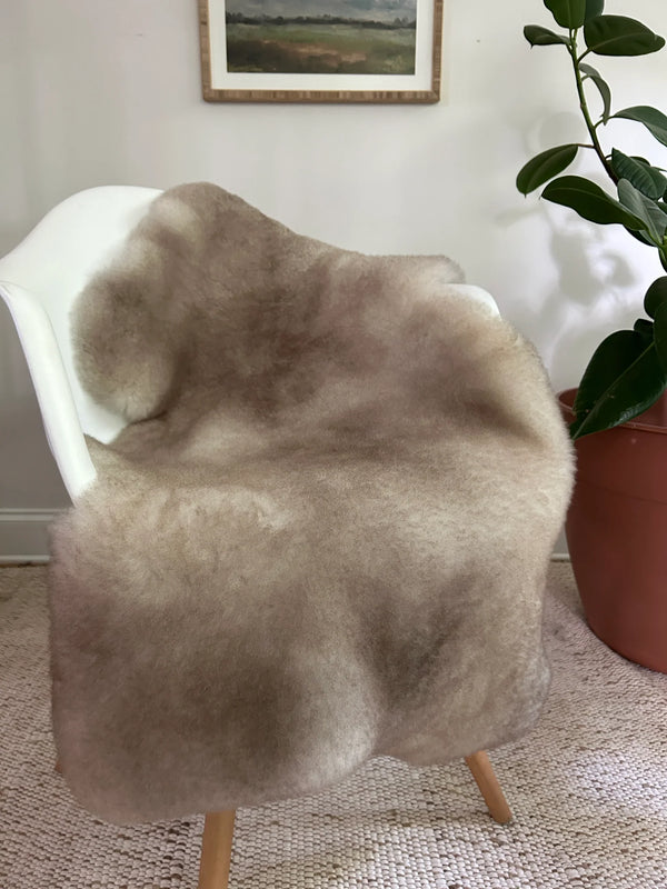 Greyish brown shortfur sheepskin over a chair