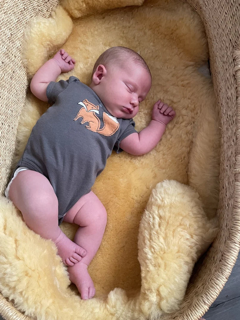 Newborn baby sleeping in medical relugan nursery sheepskin