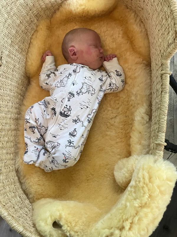 Newborn baby in a patterned outfit lying in medical relugan nursery sheepskin