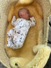 Newborn baby in a patterned outfit lying in medical relugan nursery sheepskin