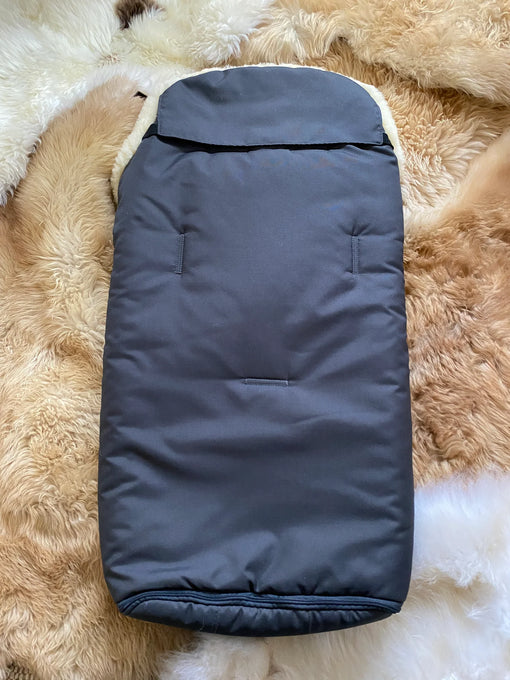 Dark blue baby bunting bag on a fluffy beige surface
