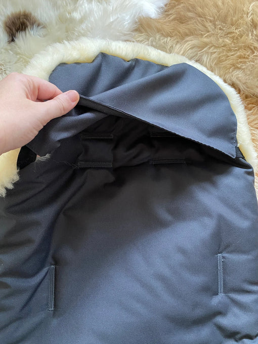 Gray fabric with a hand holding it, on a fluffy beige
