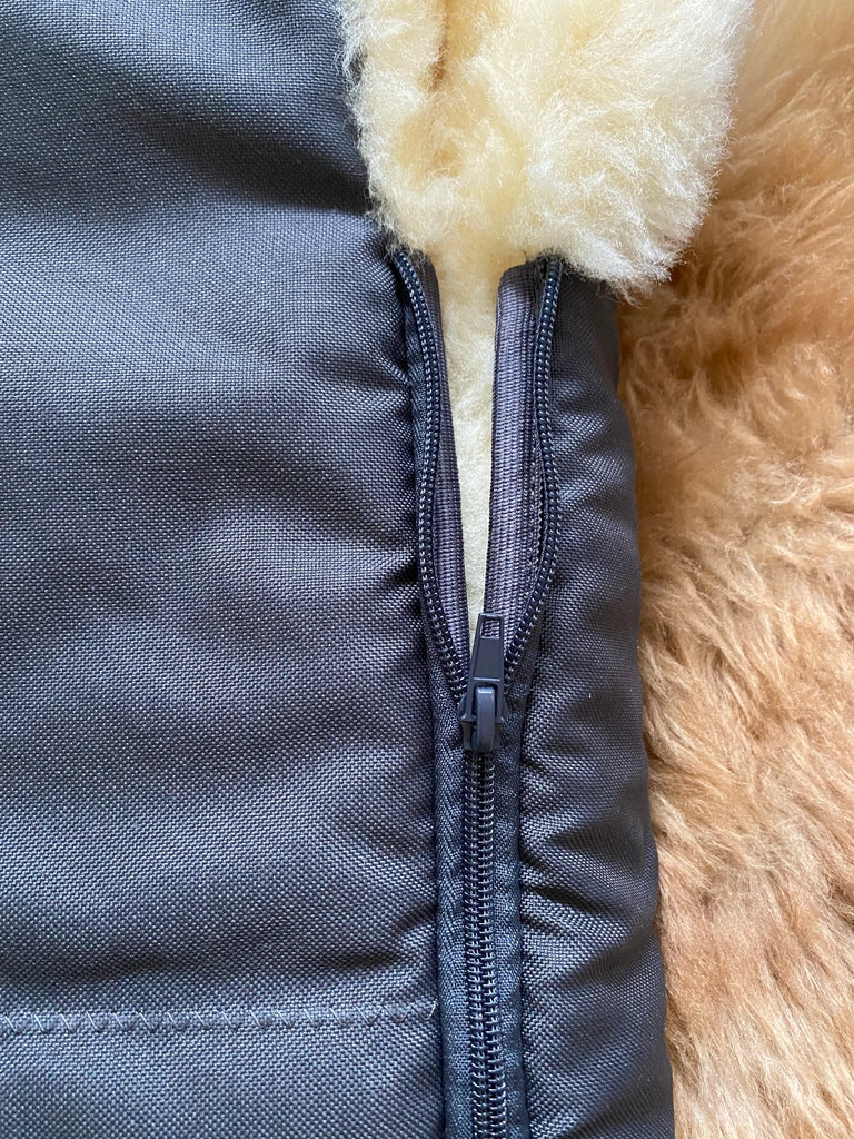 Close-up of a gray jacket with a zipper and beige interior lining.