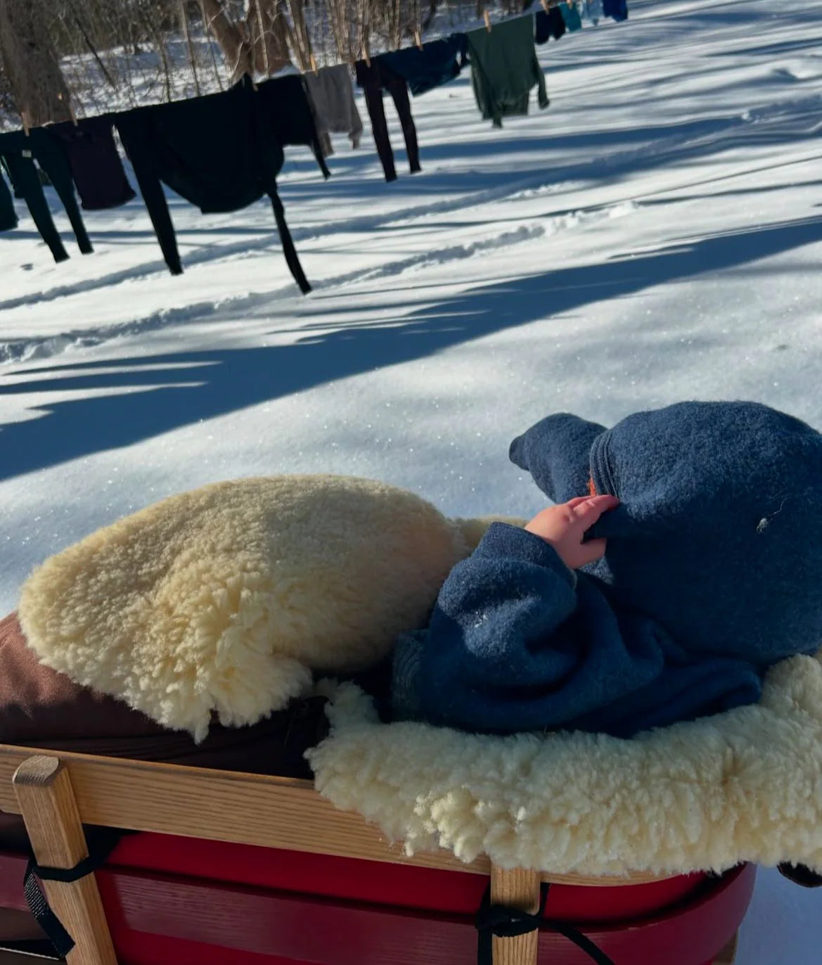 Child lying on a sled in medical sheepskin baby toddler sleeping bag