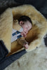 Newborn baby sleeping in a medical sheepskin baby toddler sleeping bag