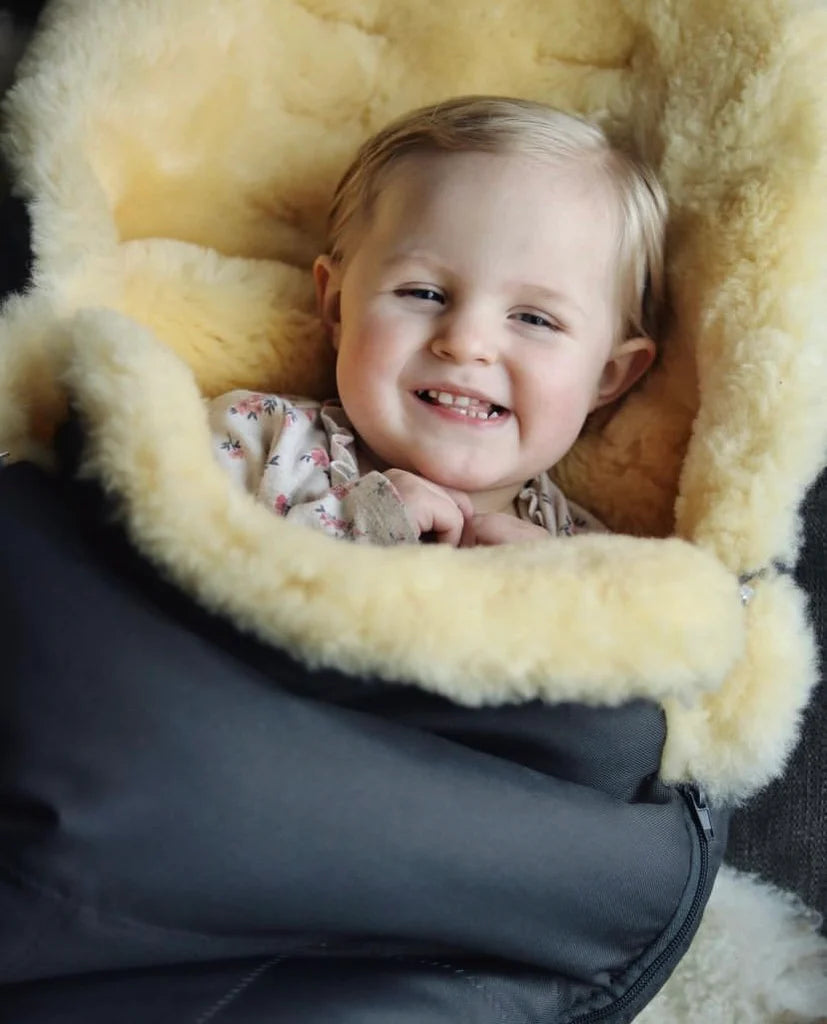 Child smiling inside a medical sheepskin baby toddler sleeping bag