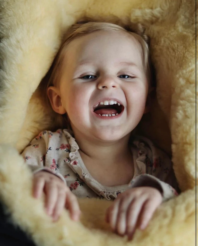 Child laughing in a medical sheepskin baby toddler sleeping bag