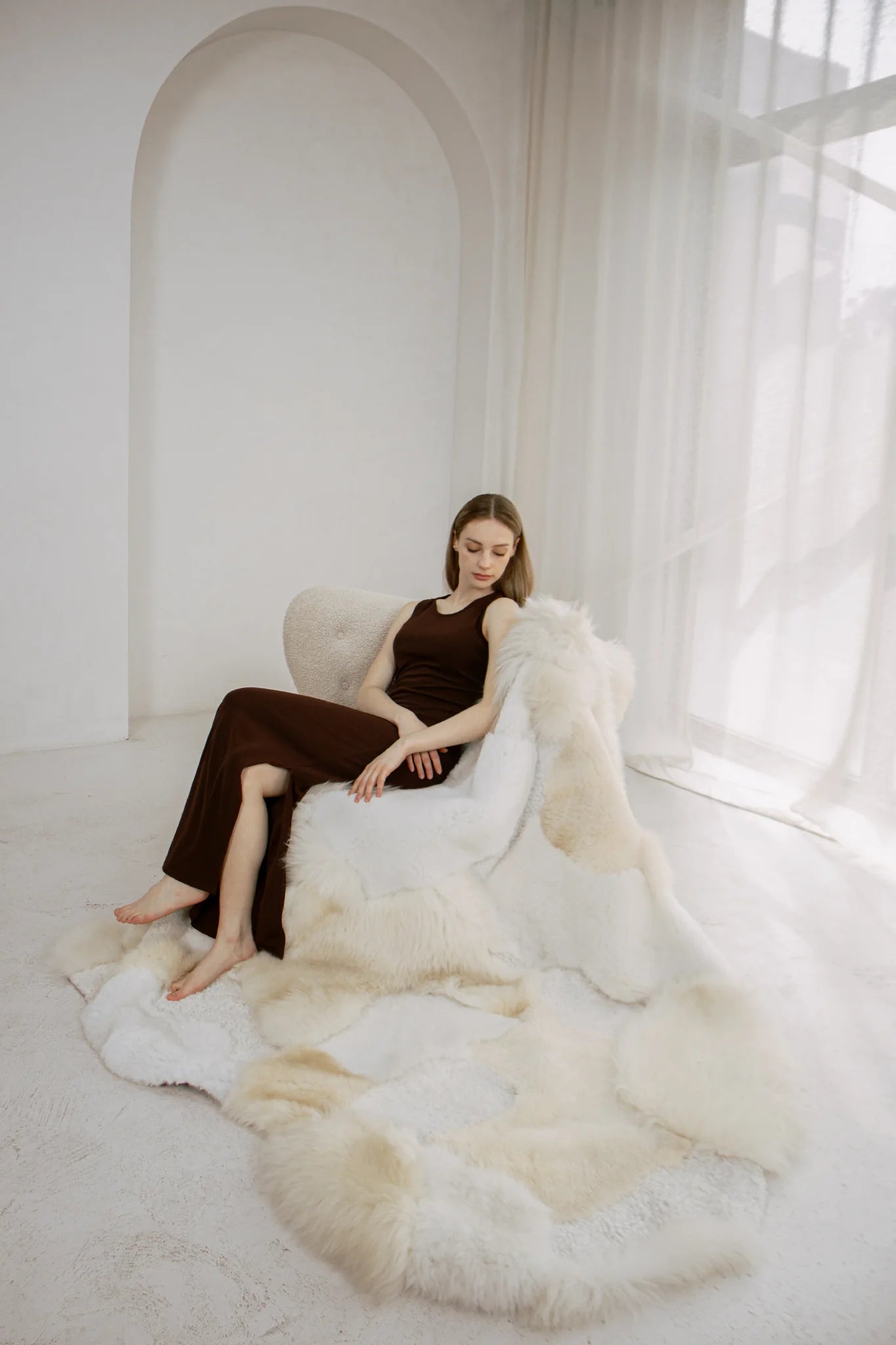 Woman sitting on a white armchair with mixed textured sheepskin rug
