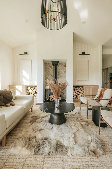 Modern living room with a white sofa, black coffee table, and mixed textured sheepskin rug