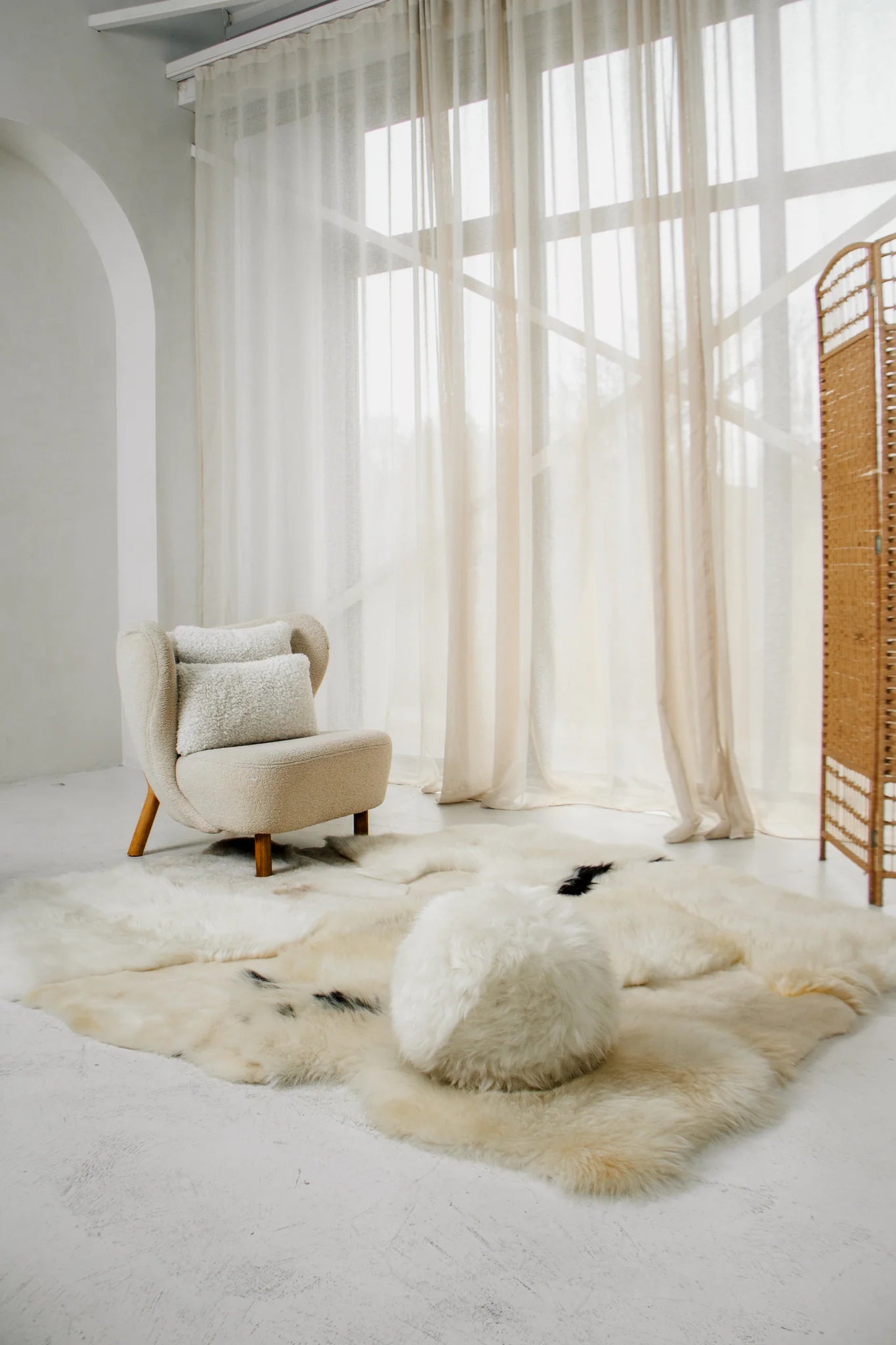 Modern interior with a beige armchair, ottoman, and mixed textured sheepskin rug