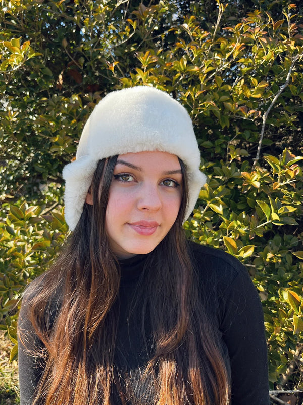 Woman wearing a sheepskin and leather pilot hat in cream