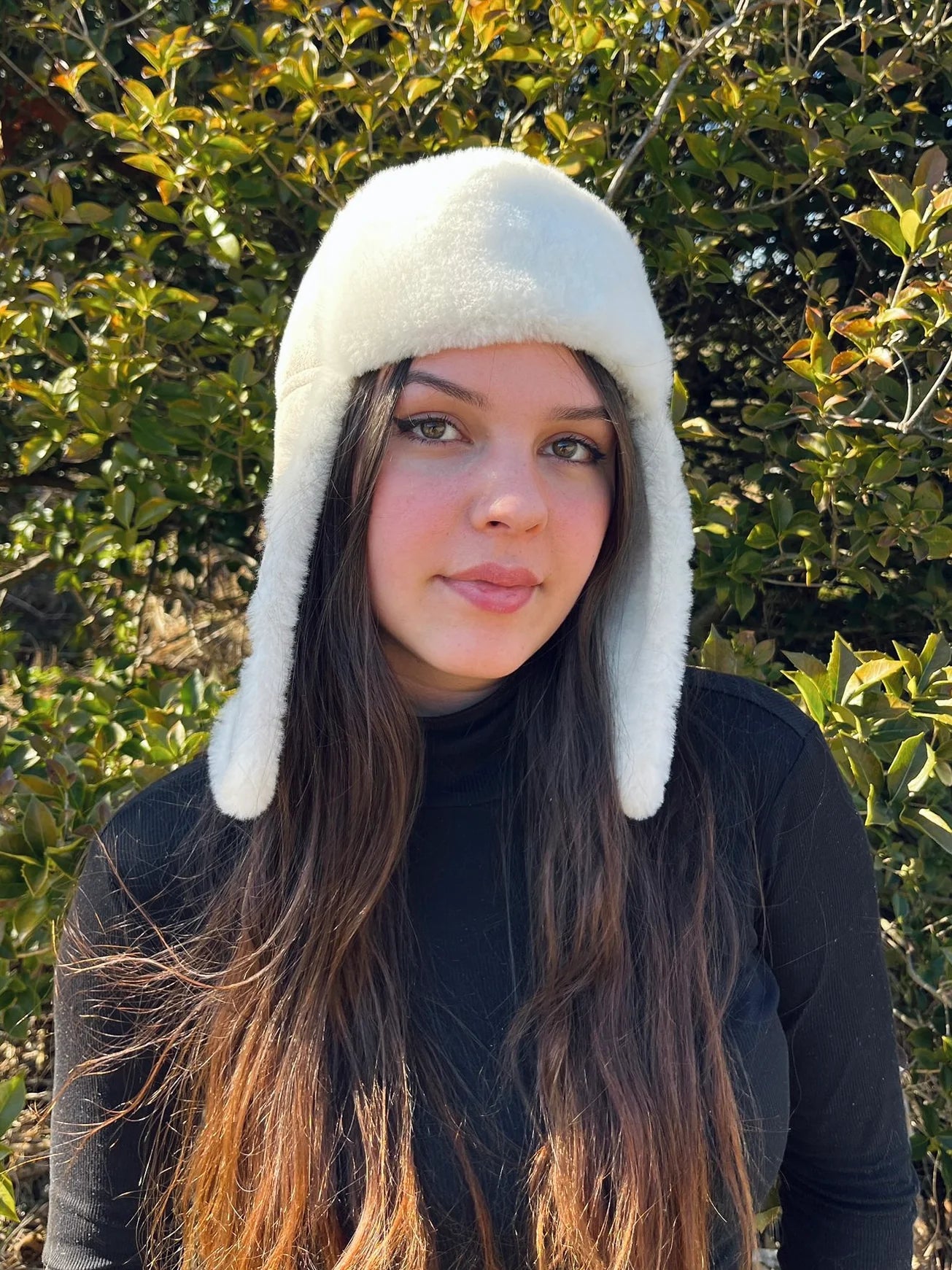 Person wearing a sheepskin and leather pilot hat in cream