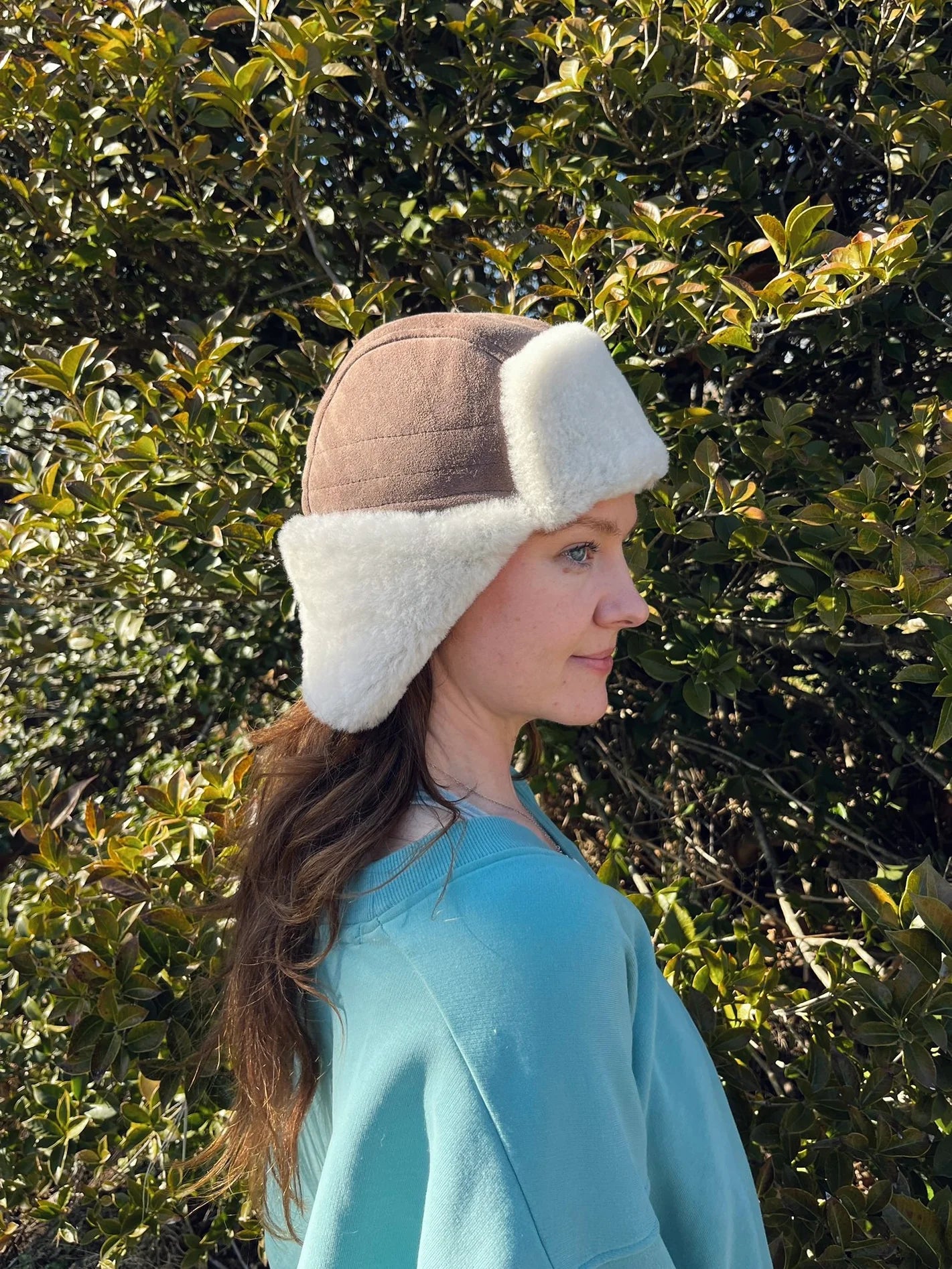 Person wearing a sheepskin and leather pilot hat in tan 