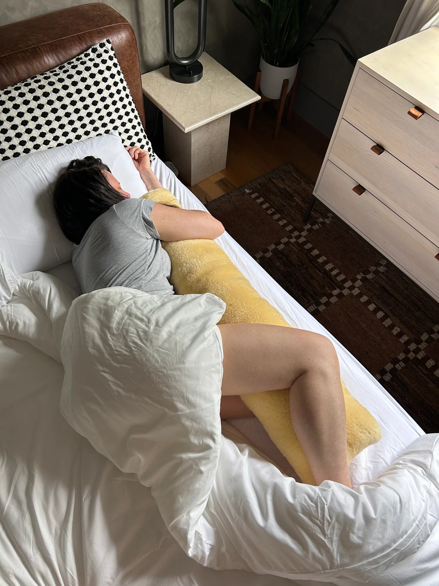 Person lying on a bed with sheepskin bodypillow case
