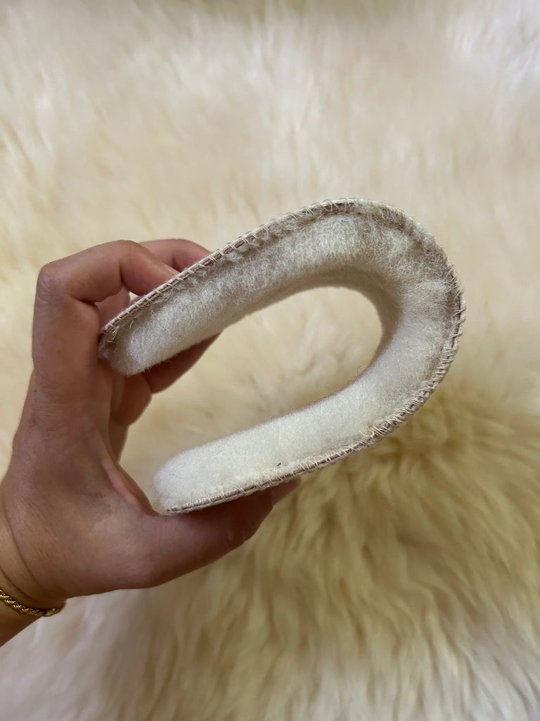 Hand holding a curved, sheepskin insoles