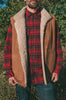 Person wearing a red plaid shirt, brown sheepskin mens vest with white fur lining, and blue jeans outdoors.