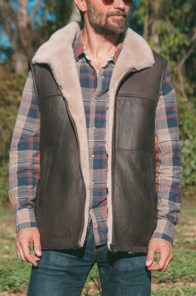 Man wearing a plaid shirt, leather sheepskin mens vest
