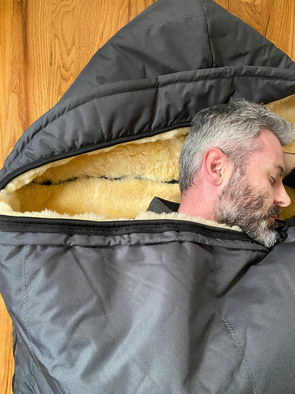 Man peeking out from inside a sheepskin sleeping bag