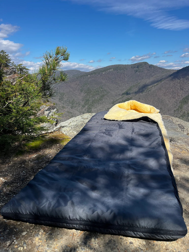 Sheepskin sleeping bag on a rock with mountain view