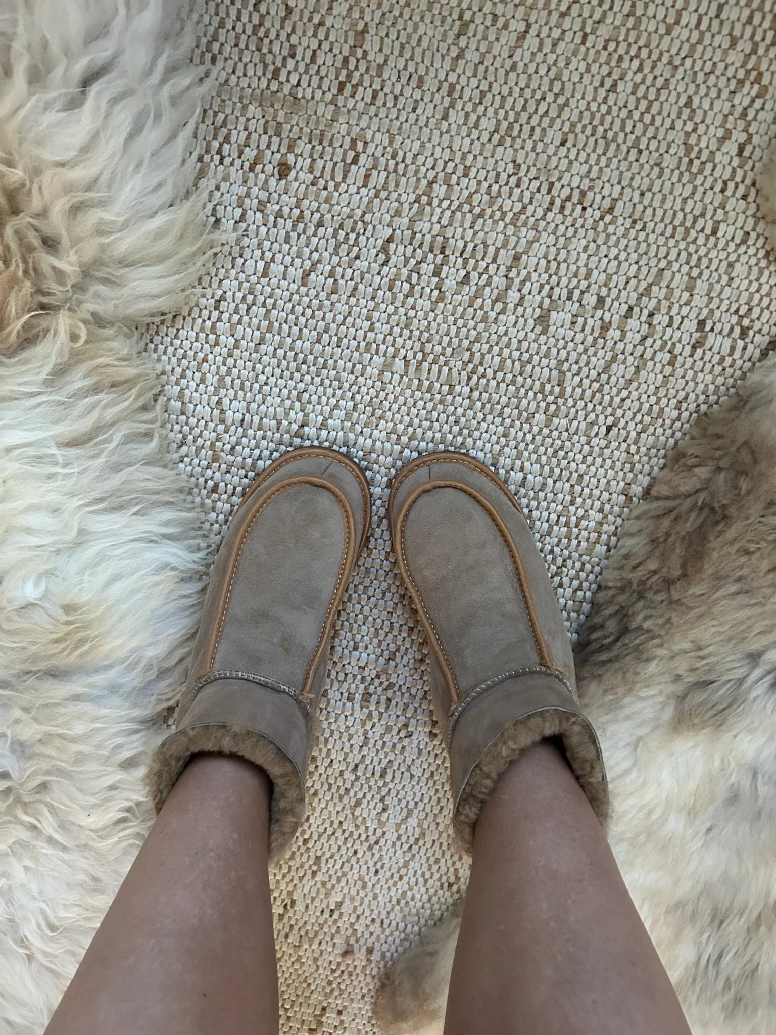 sheepskin slippers on a textured rug with fur border