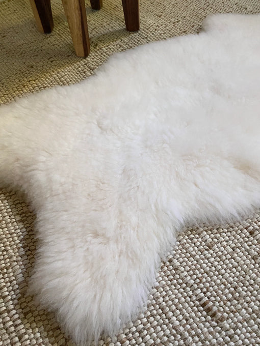Small white nursery pelt on a textured beige floor