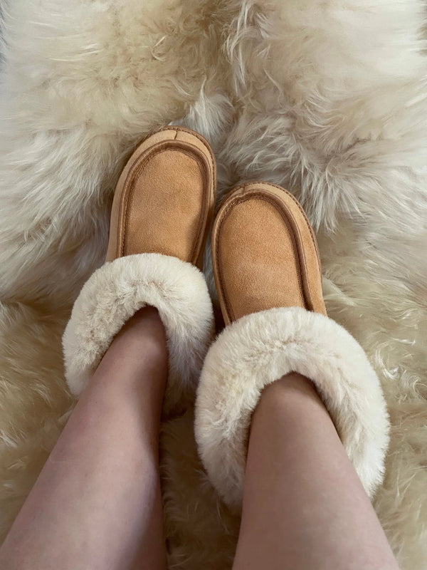 Close-up of the white sheepskin lining inside tan suede slippers