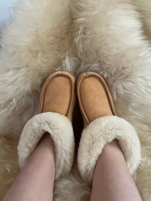 Close-up of the white sheepskin lining inside tan suede slippers