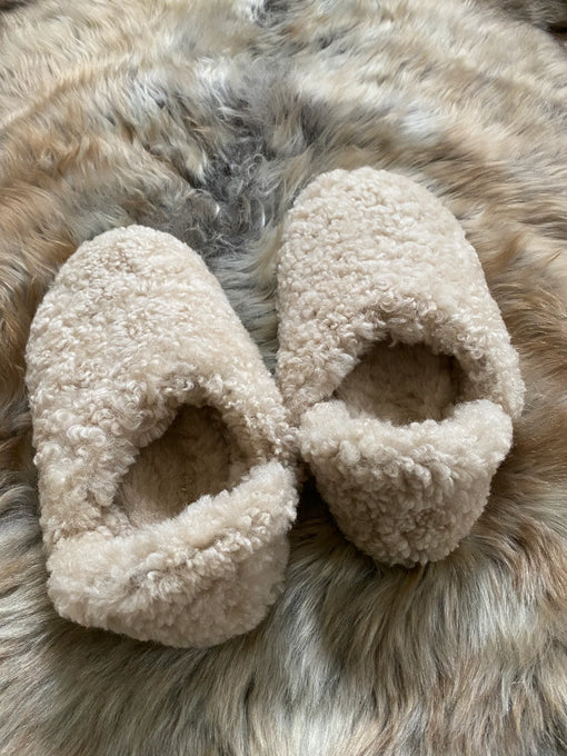 Pair of beige slippers on a fur surface
