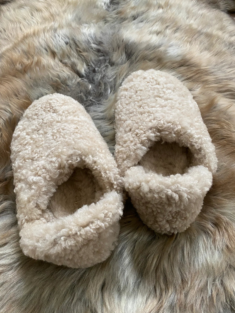 Pair of the everyday slip on tan shearling sheepskin on a fur surface