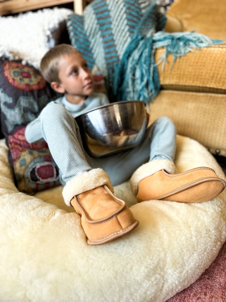 Child wearing brown slippers sitting on the snugly